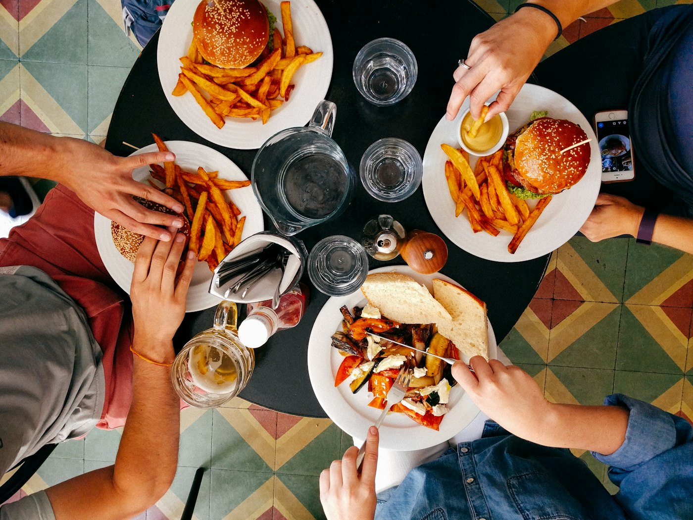 Grupo de amigos comendo hambúrguer e batata frita em uma mesa